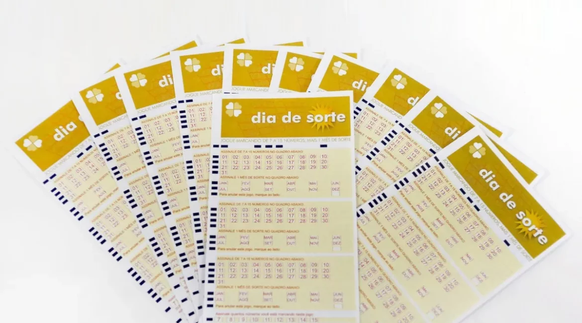 Vários volantes do Dia de Sorte dispostos em leque sobre superfície branca, com números e meses do ano destacados para apostas.