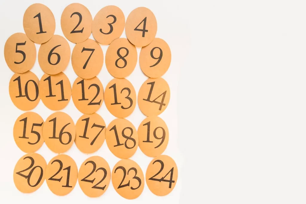 Imagem com cartões ovais em papel laranja, cada um contendo números de 1 a 24 em cor preta. Ideal para ensino de números e atividades educativas.