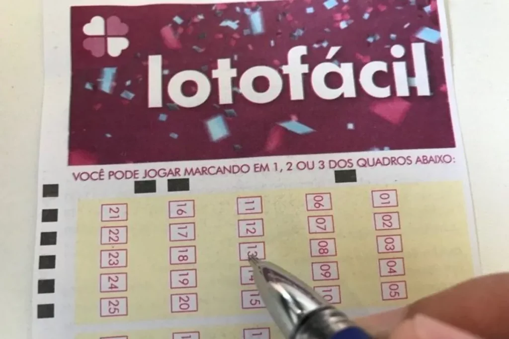 Pessoa marcando número no volante da Lotofácil com caneta, destacando o processo de escolha dos números na loteria da Caixa Econômica Federal