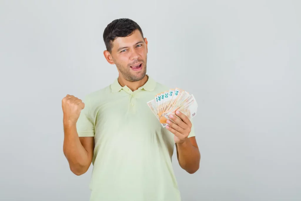 Homem segurando notas de dinheiro com expressão de felicidade, simbolizando sorte, ganhos ou sucesso financeiro.