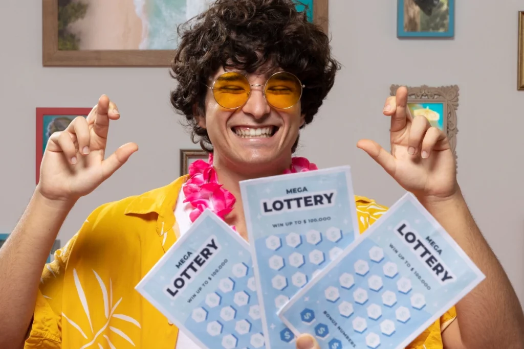Homem sorrindo com os dedos cruzados e, na sua frente, 3 bilhetes de loteria