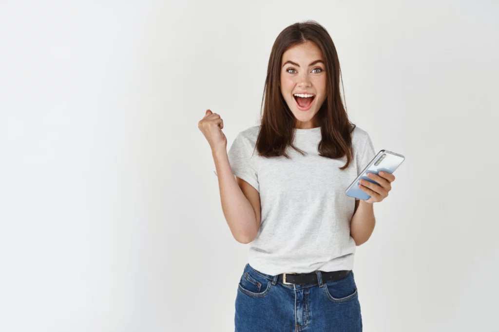 Mulher com o celular na mão, comemorando