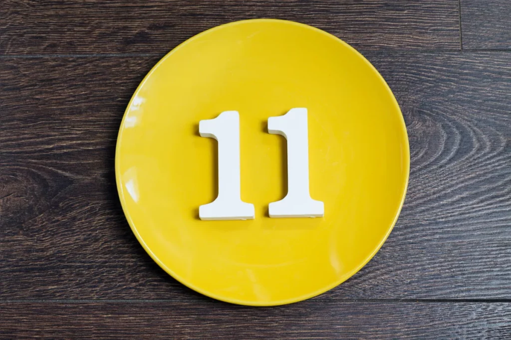 numeros brancos formando 11 posicionados sobre um prato amarelo em fundo de madeira