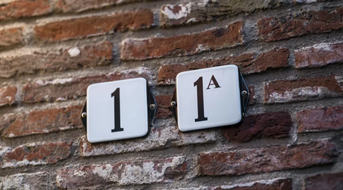 placas com o numero 1 e 1a fixadas em uma parede de tijolos formando o numero 11