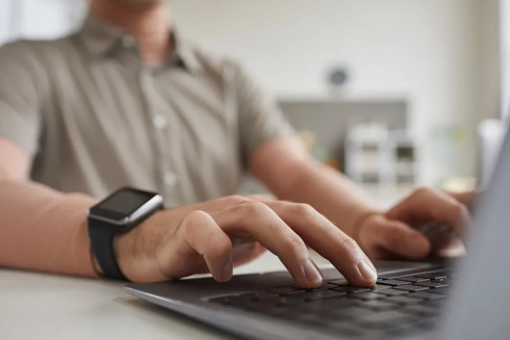 Pessoa digitando no teclado de um notebook enquanto trabalha ou acessa ferramentas online.