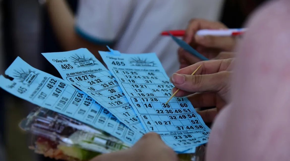 pessoas segurando cartelas de loteria e marcando números com caneta em ambiente coletivo